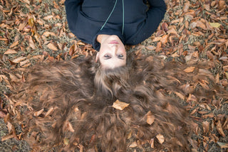 Femme aux longs cheveux bruns allongée dans les feuilles d'automne